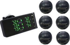 Handheld digital tire pressure gauge showing readings with six black sphere sensors nearby likely TPMS sensors